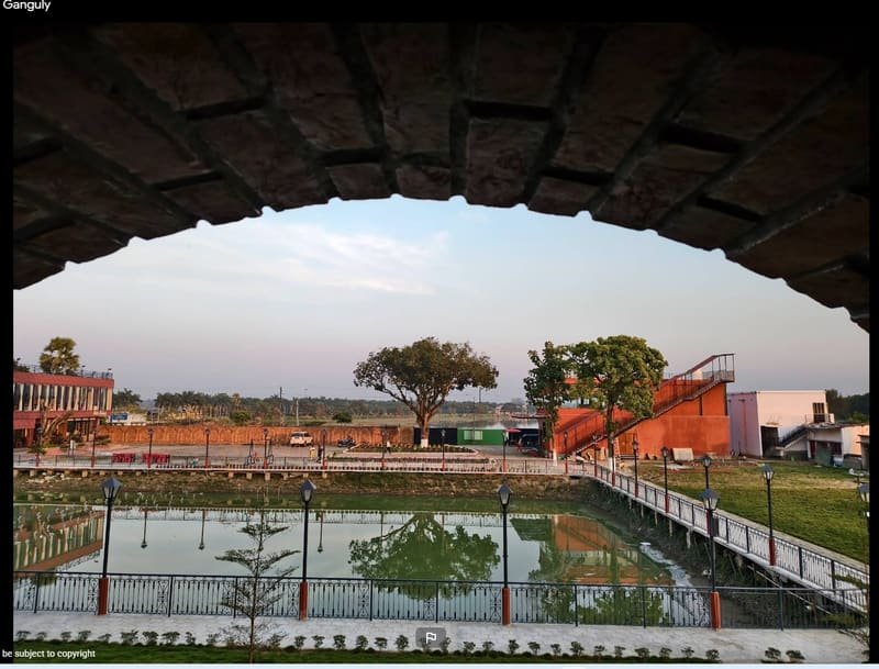 The view over water and lawn, framed by a brick arch