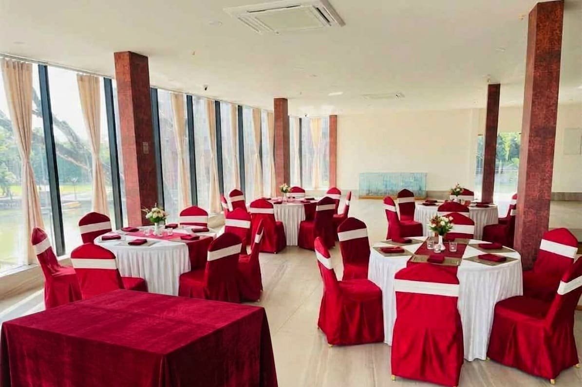 A banquet hall laid with red and gold covers along a long window