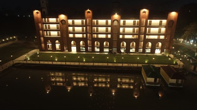 The lit brick arcade mirrored in the water at night