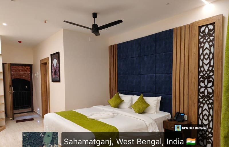 A room with a padded blue headboard and green throw